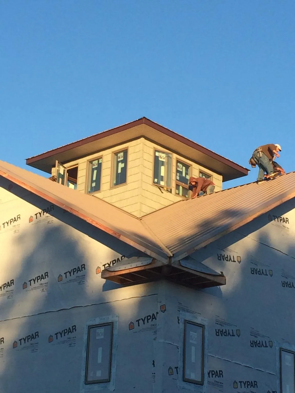 Roofers working around a rooftop cupola on a new metal roof at sunset — Roof Waterproofing in Stratford by Roofing Brothers